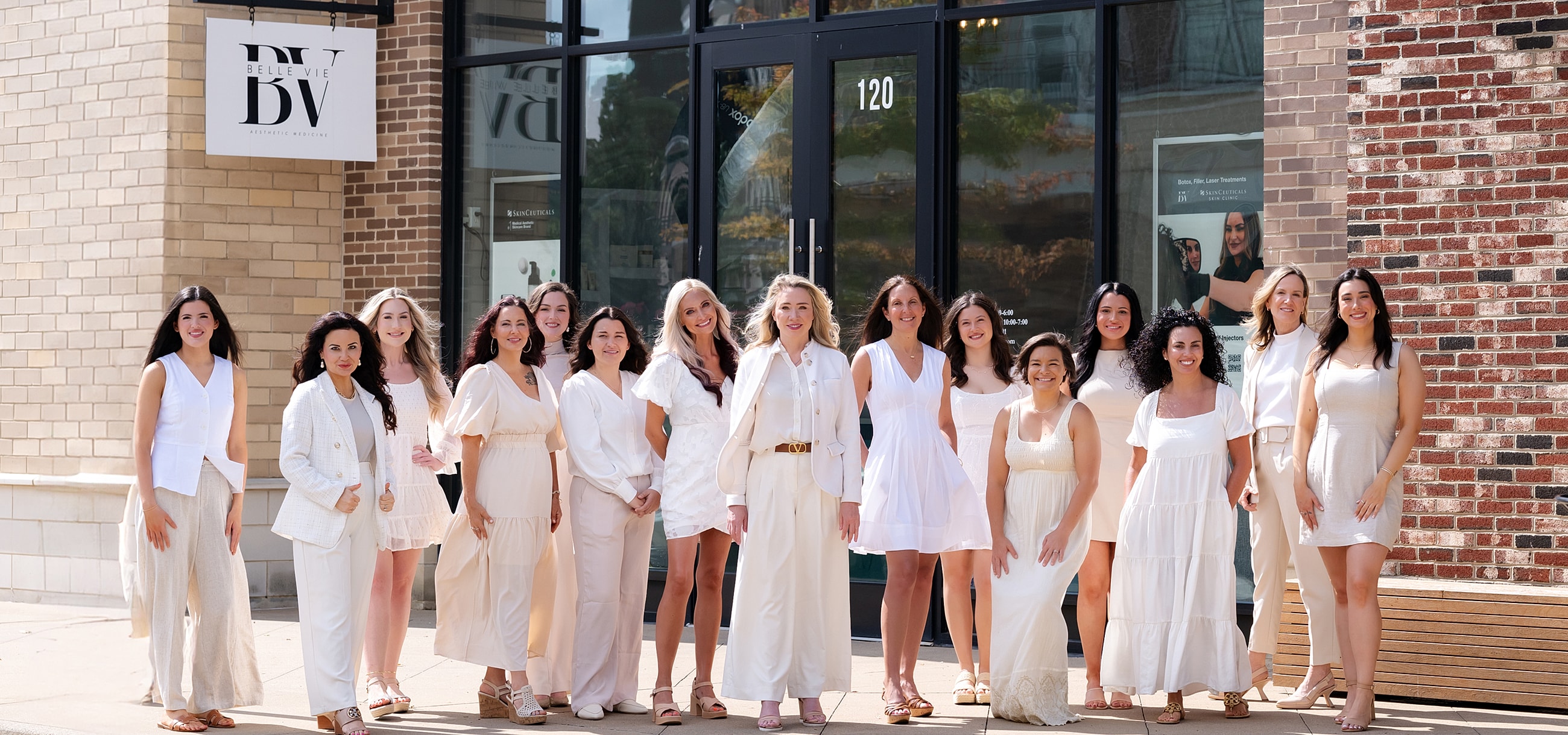 Group of women in white outfits outside building.