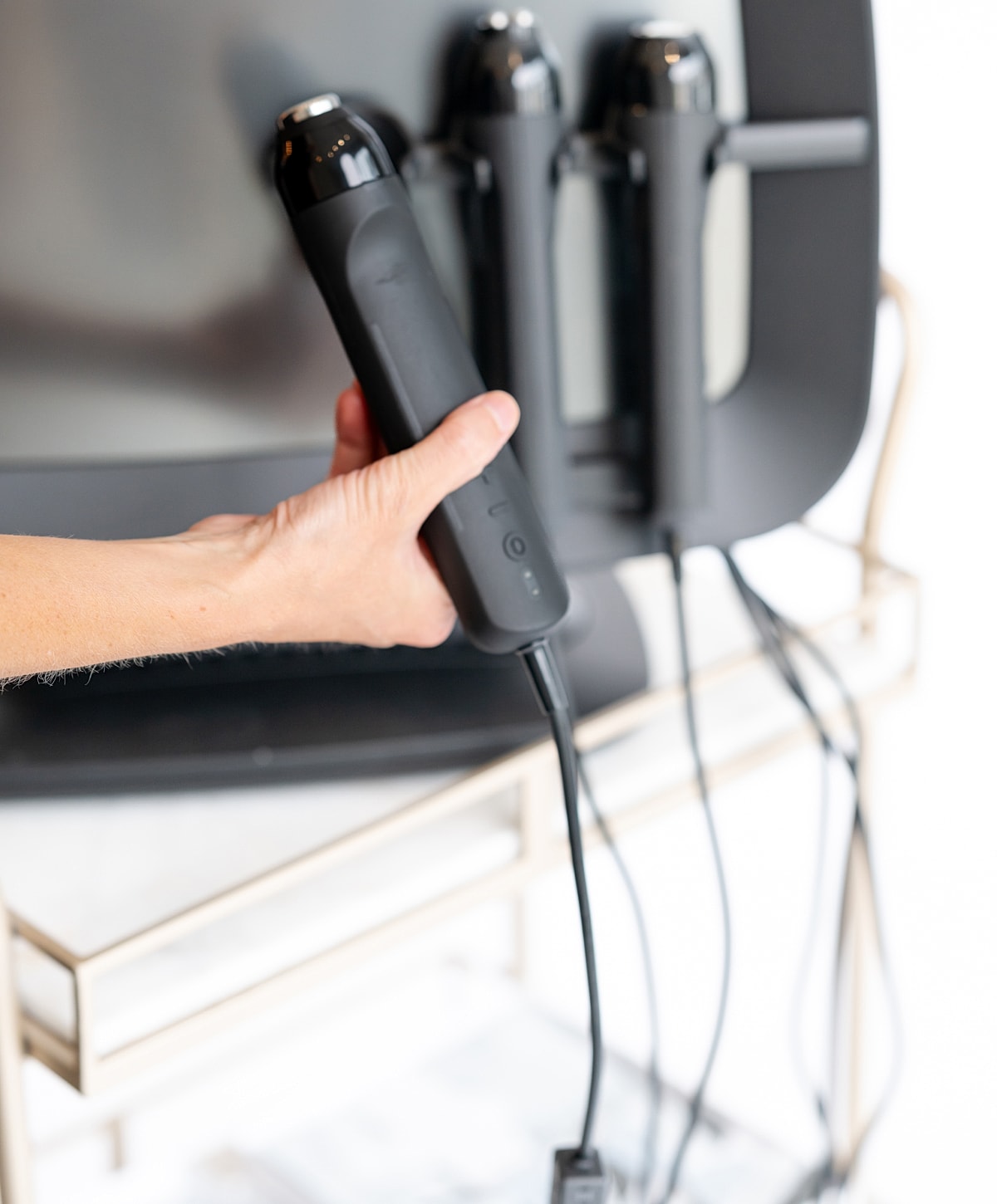 Hand holding a black device near a wall.