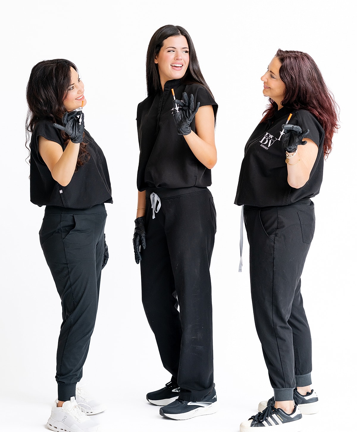 Three women smiling with pencils in gloves.