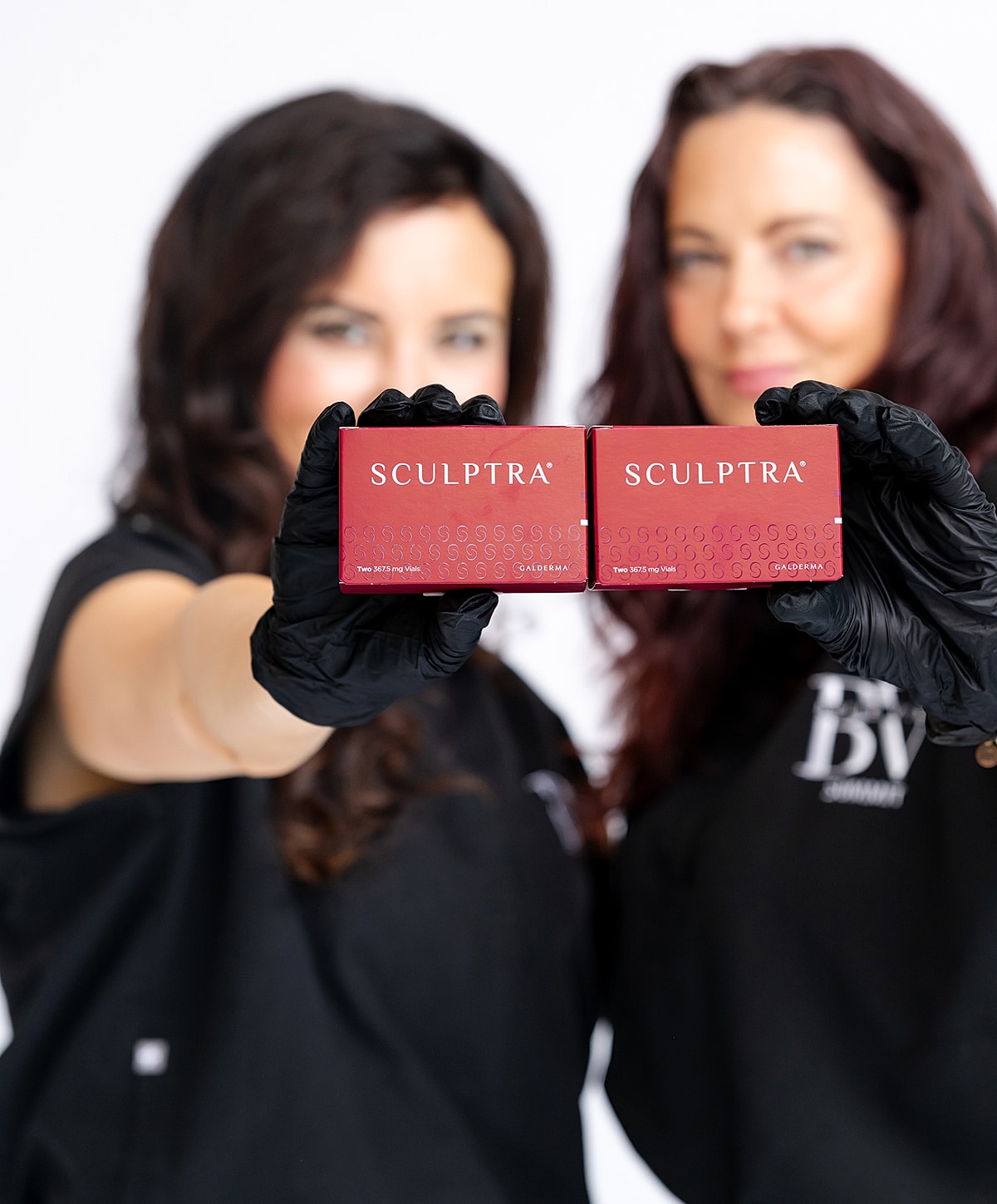 Women holding Sculptra product boxes together.
