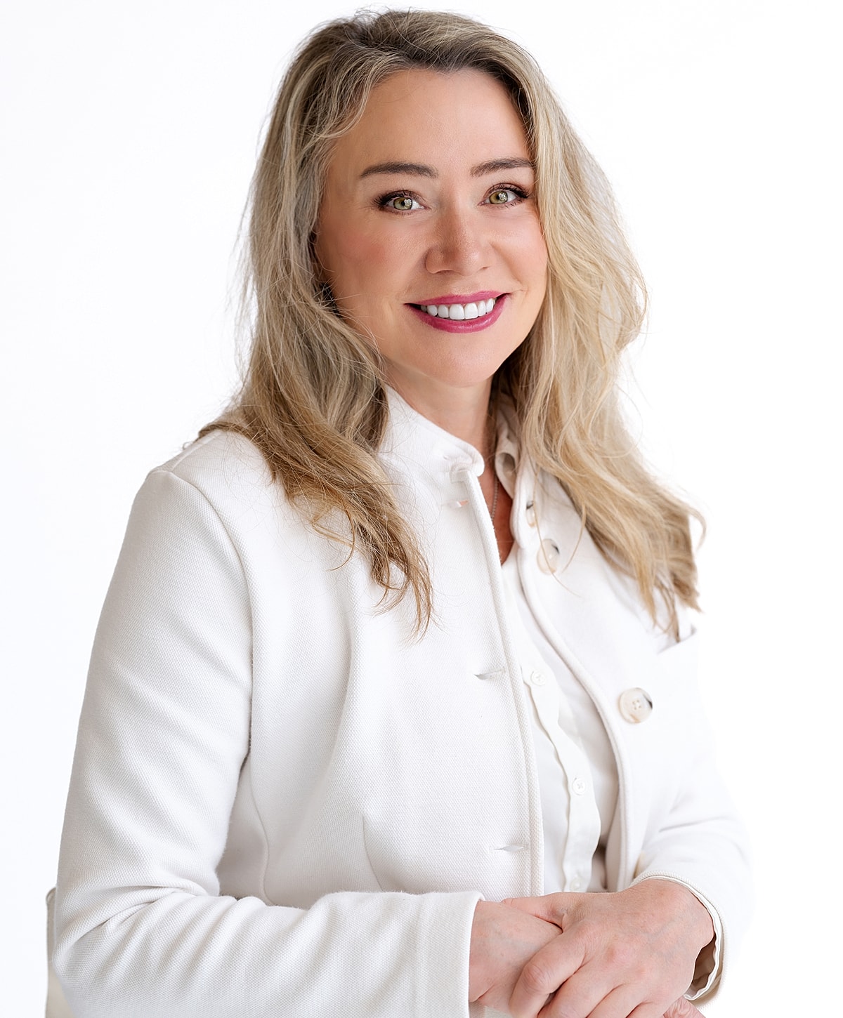 Smiling woman in white jacket, professional portrait.