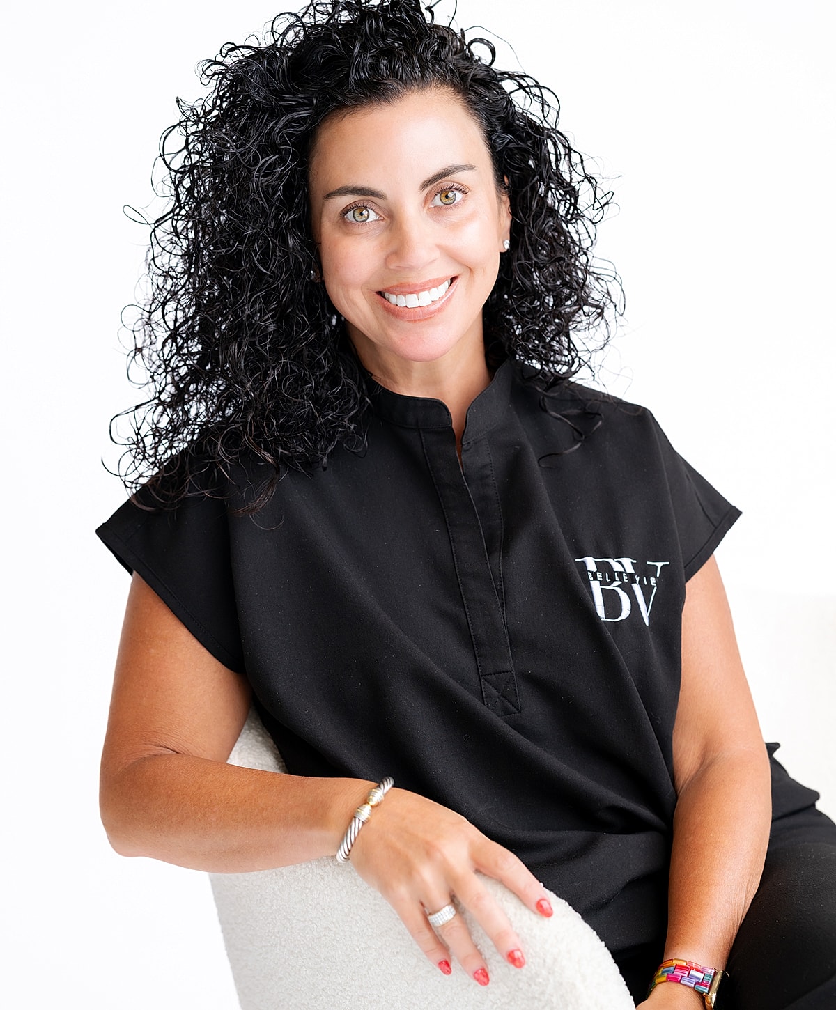 Smiling woman with curly hair in a black top.