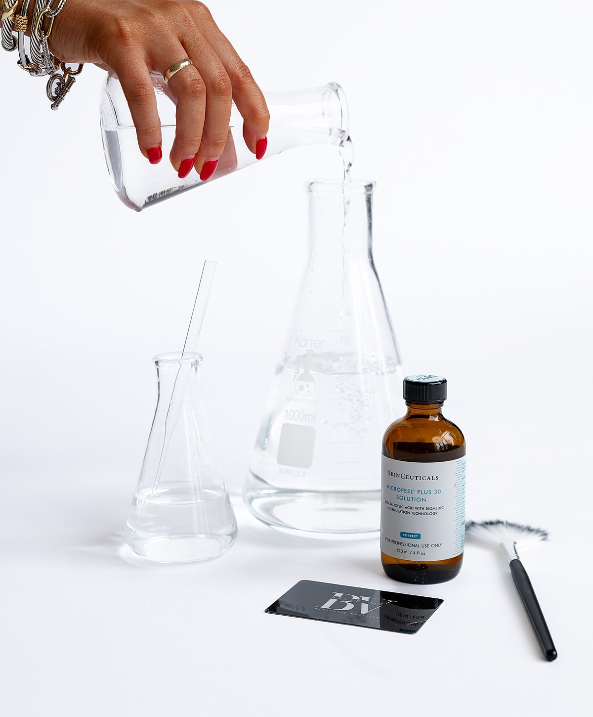 Hand pouring liquid into laboratory glassware.