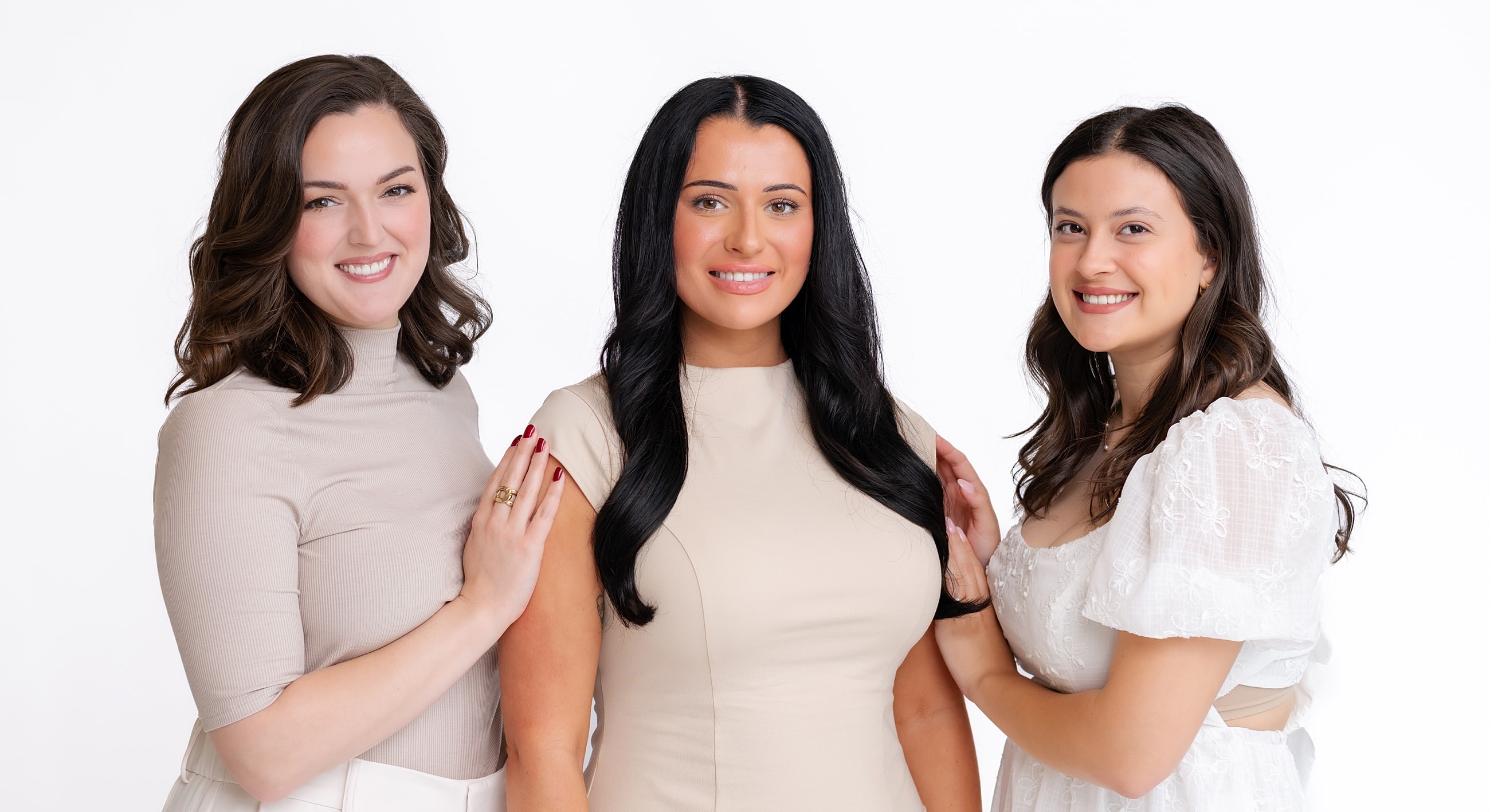 Three women posing together in studio setting.
