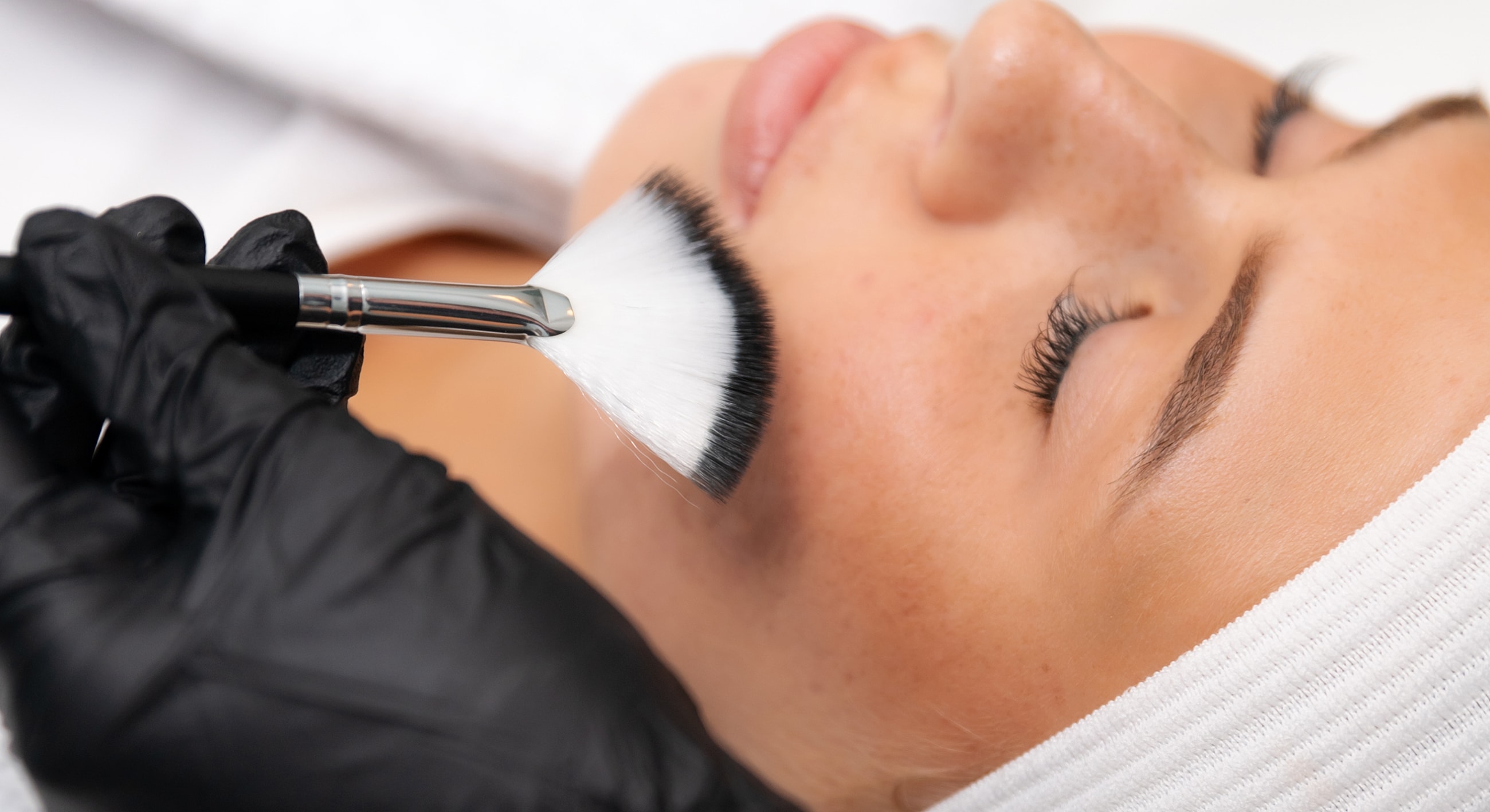 Applying cosmetic treatment on a woman's face.