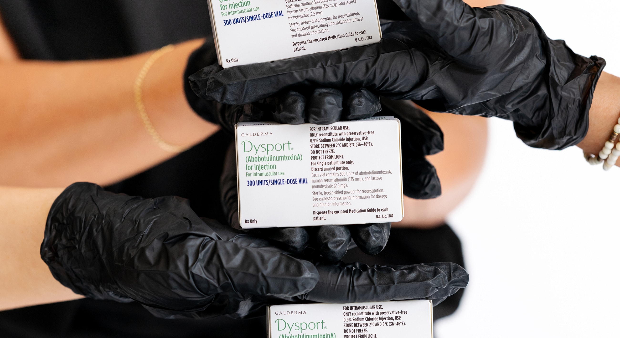 Dysport medication vials held by gloved hands.