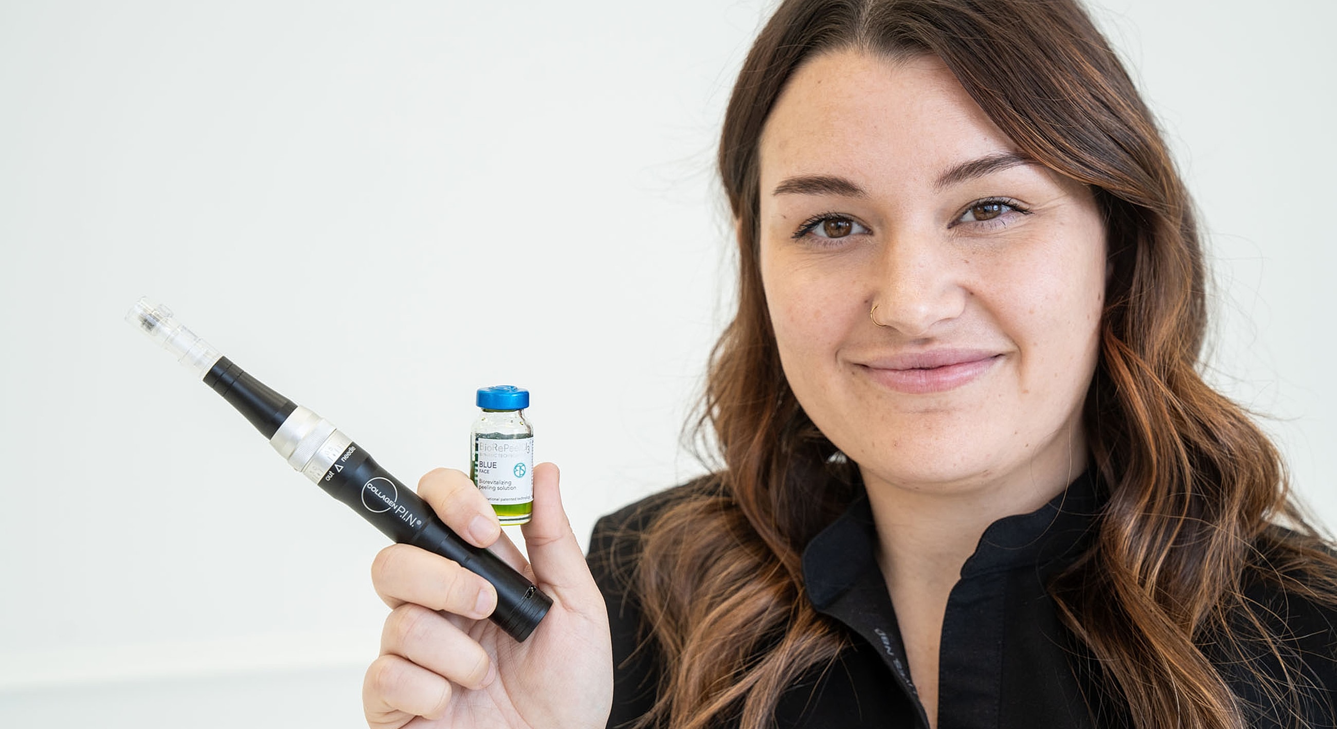 Woman holding microneedling device and vial.